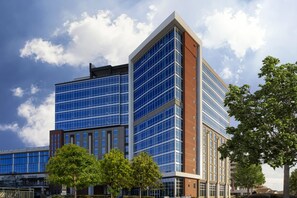 A modern building with a glass facade and a corner entrance. - AC Hotel Charlotte Ballantyne (Charlotte)