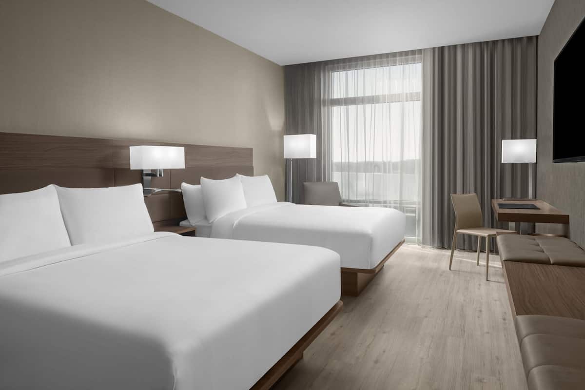 Een hotelkamer met twee bedden, een bureau, een stoel en een televisie.
