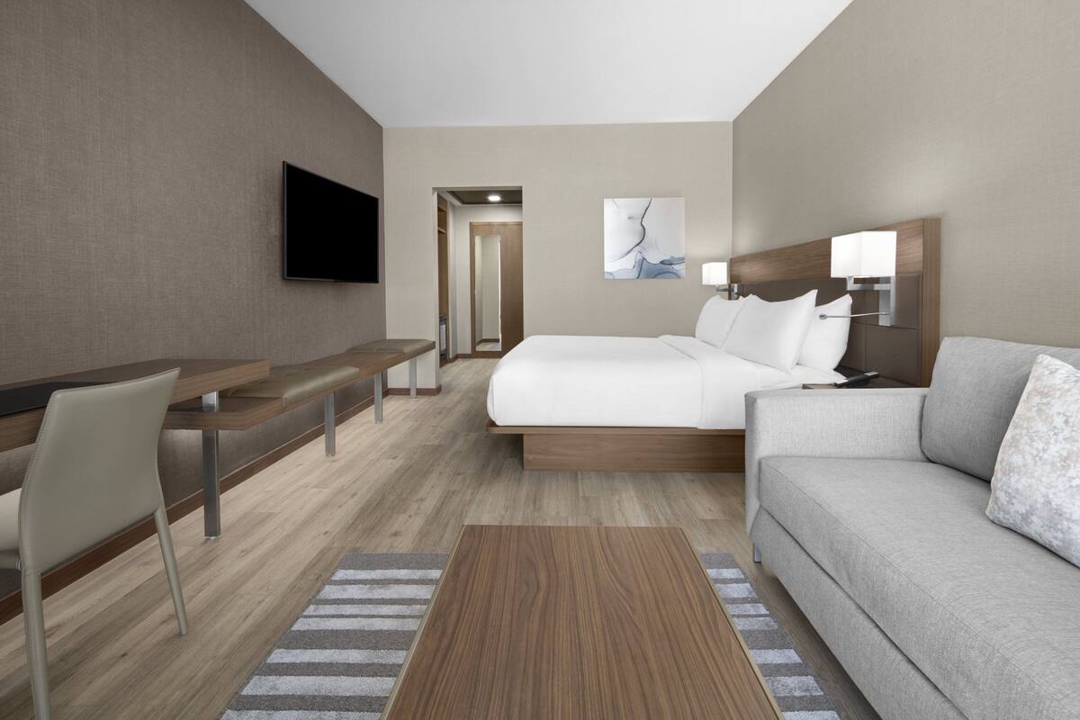 Een moderne hotelkamer met een bed, een slaapbank, een bureau en een televisie.