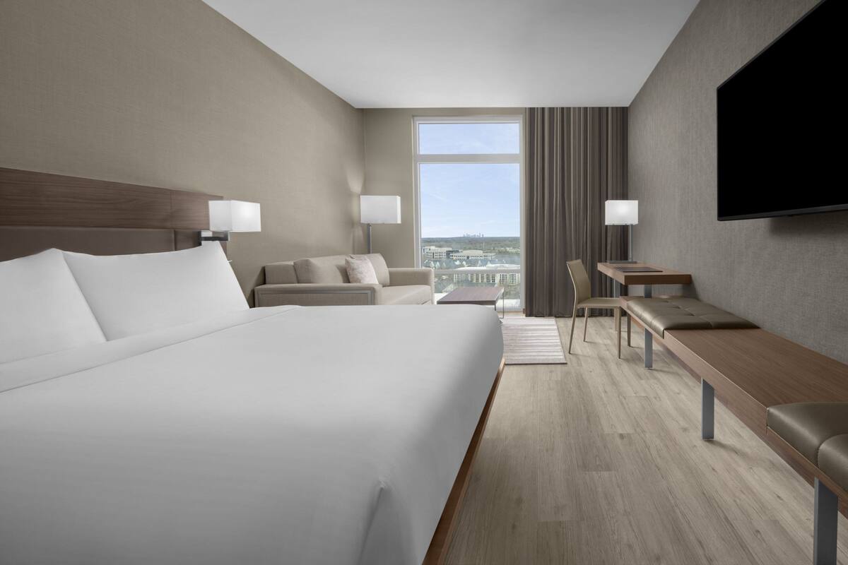 Een moderne hotelkamer met een groot bed, een bank, een bureau en een televisie.