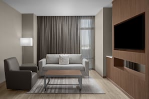 A modern living room with a sofa, armchair, coffee table, and TV wall unit. - AC Hotel Charlotte Ballantyne (Charlotte)