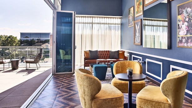 A modern living room with a blue accent wall, a sofa, and a dining area with chairs and a table.