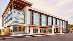 A modern hotel with a glass facade, large windows, and a flat roof.
