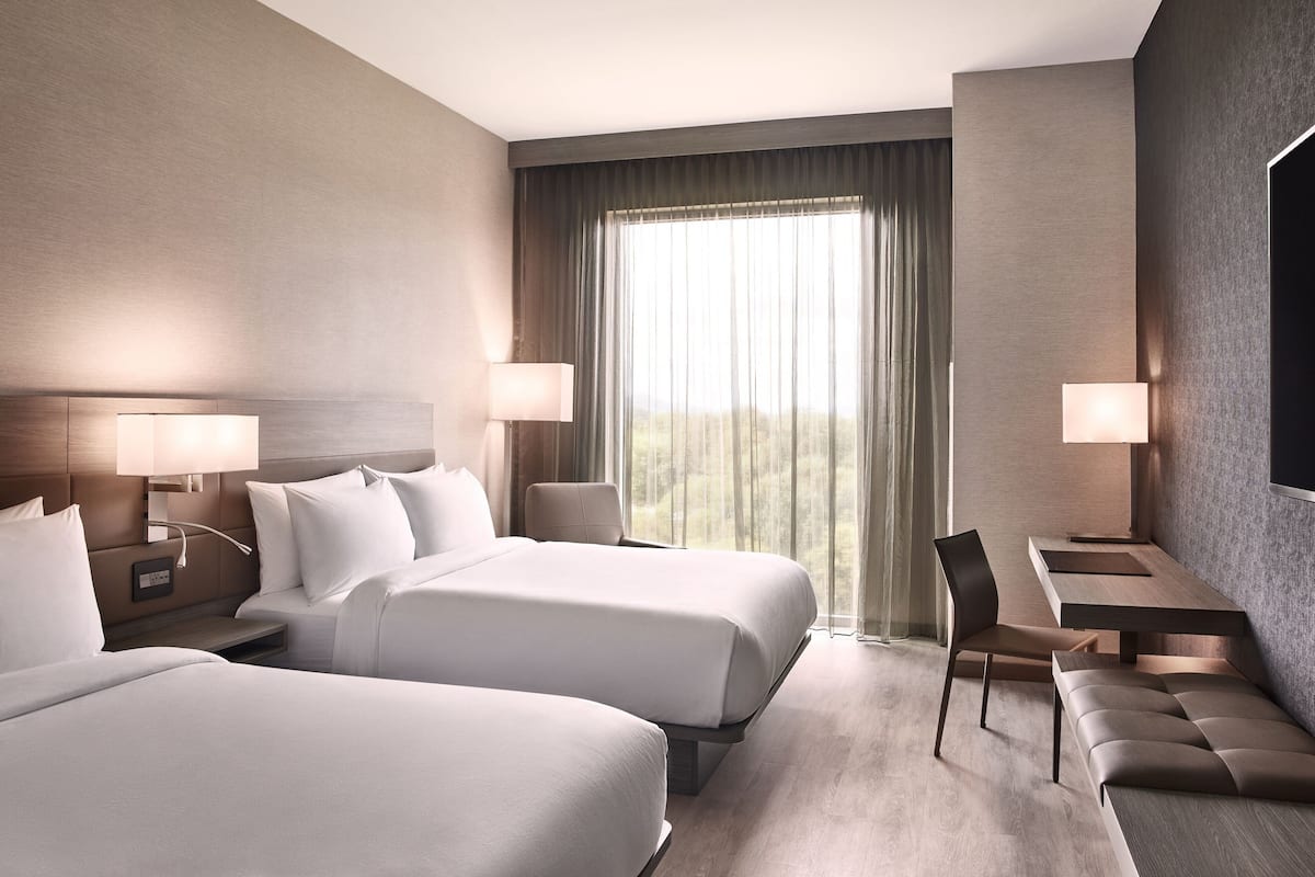Una habitación de hotel con dos camas, un escritorio, una silla y un televisor.