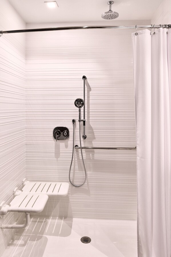 A walk-in shower with a handheld showerhead, a handheld showerhead, and a handheld showerhead.