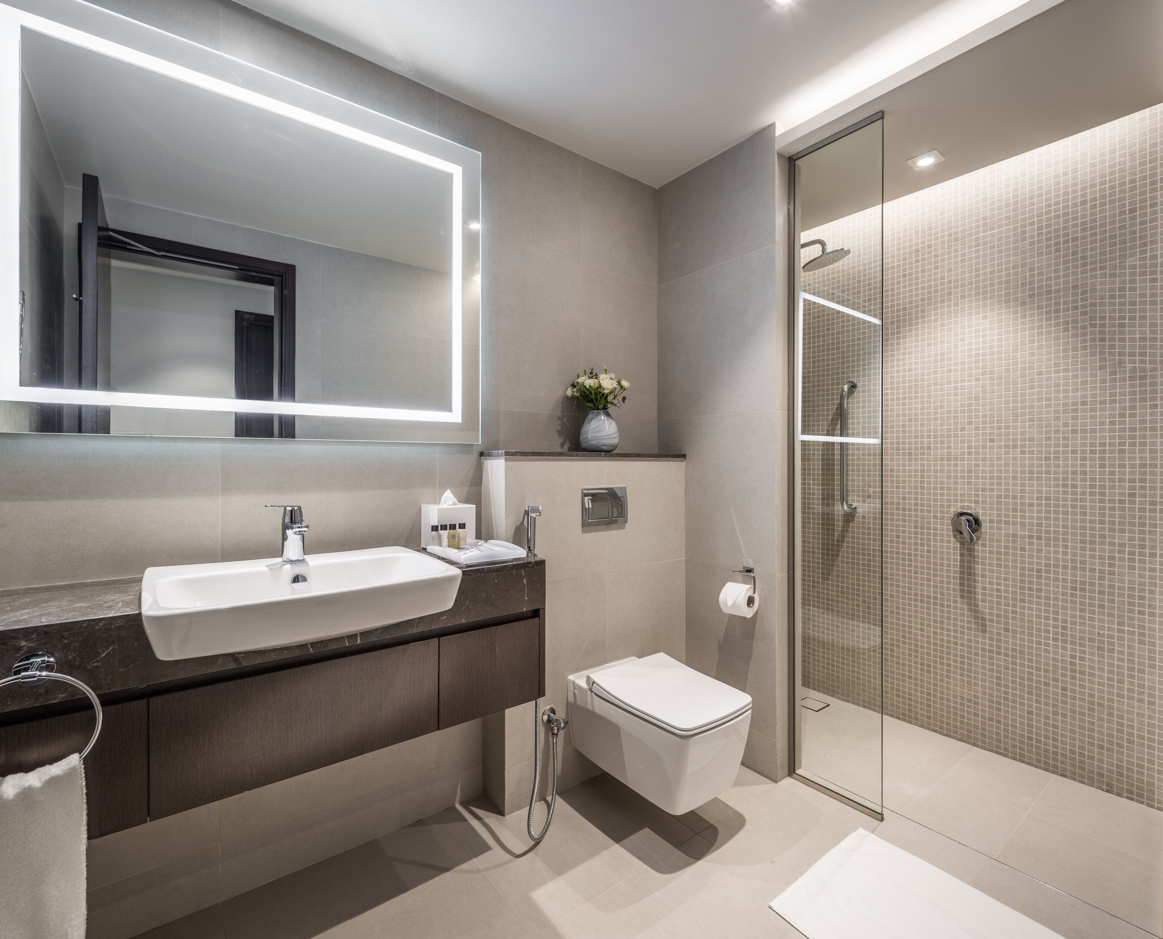 A modern bathroom with a large mirror, a sink, a toilet, and a shower area.