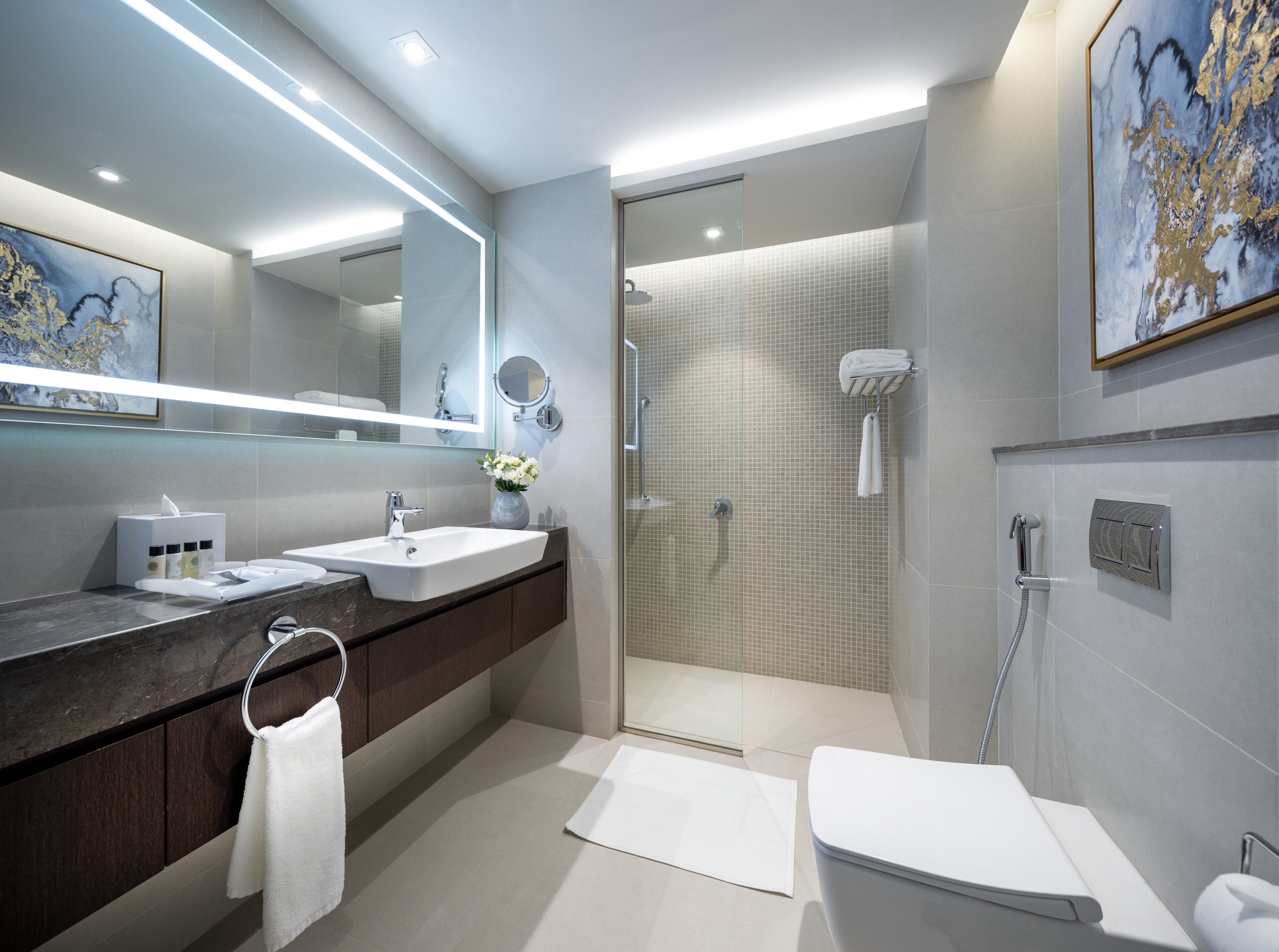 A modern bathroom with a large mirror, a sink, a toilet, and a shower area.