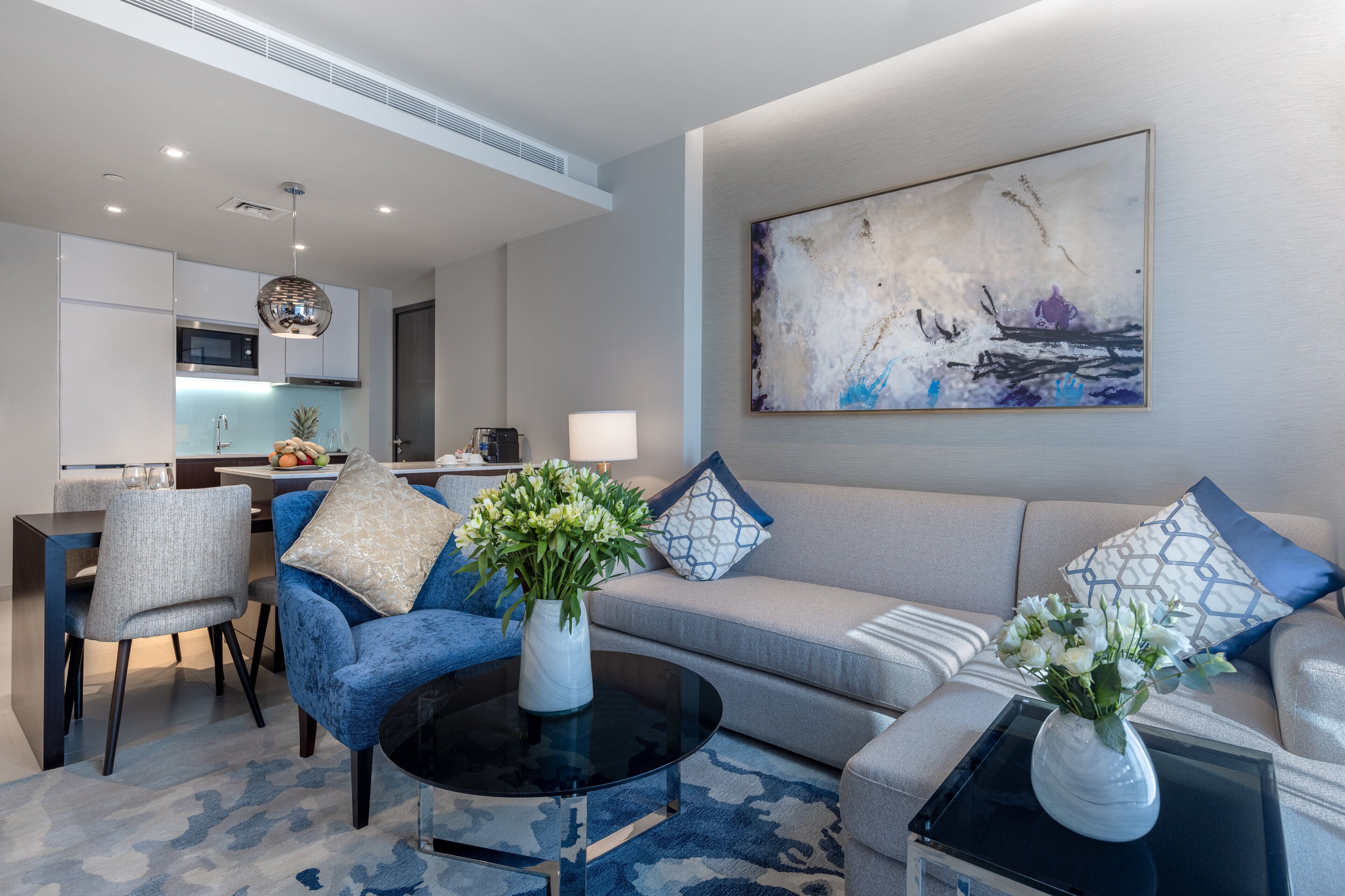 Una sala de estar moderna con un sofá, sillas, una mesa de centro y un comedor con una cocina al fondo.