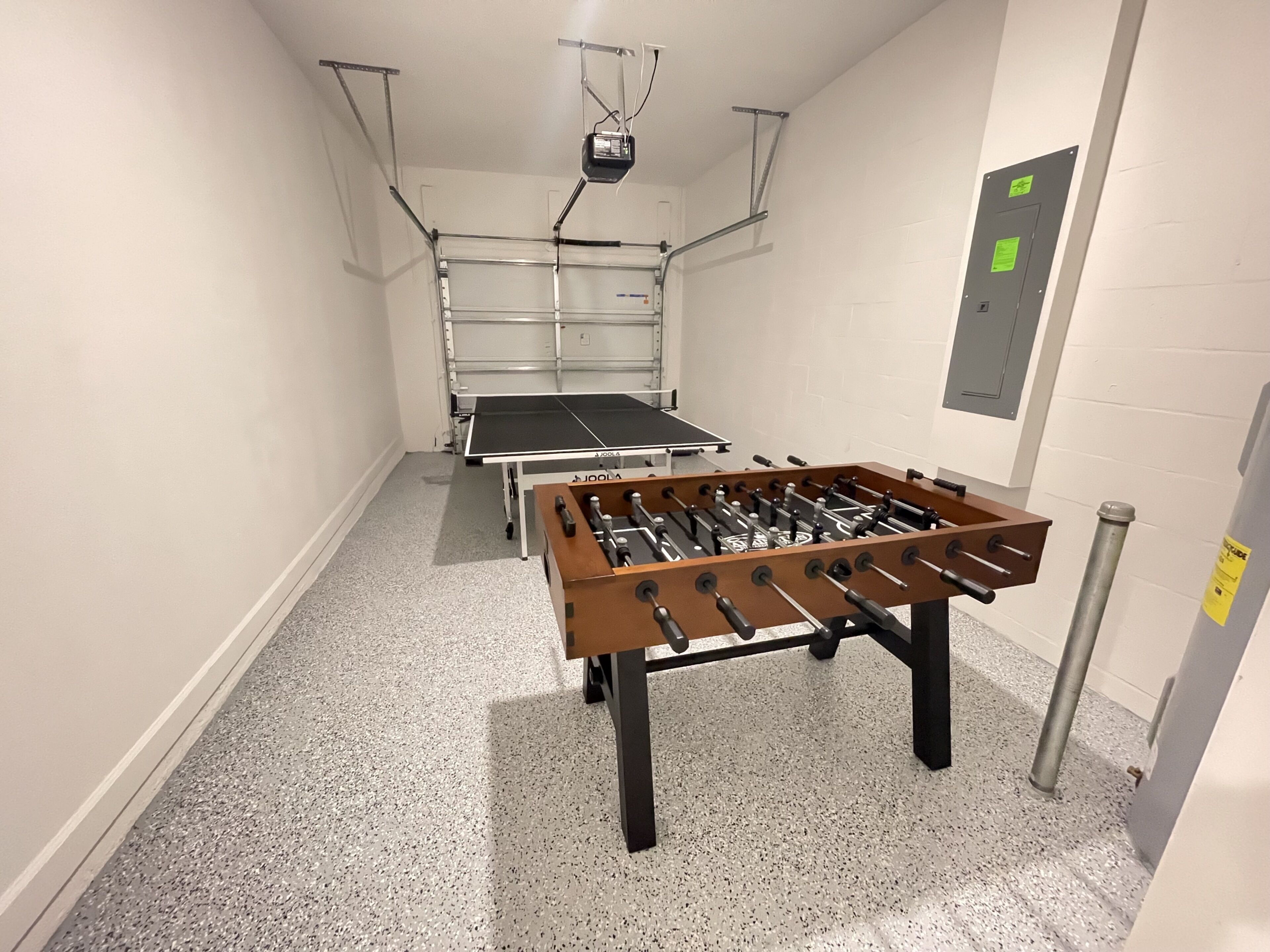 A narrow hallway with a foosball table and a ping pong table.
