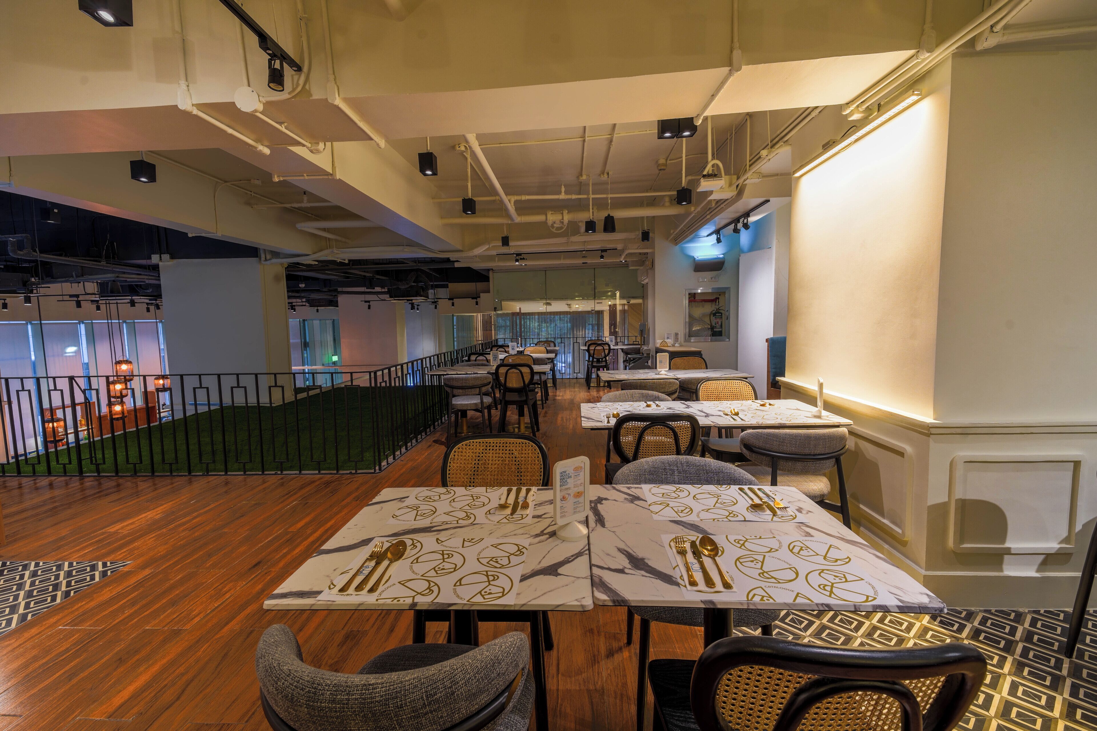 Un restaurante con mesas dispuestas para comer, una escalera y vistas de la ciudad.