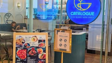 Een modern café interieur met een menubord, een bord met kledingvoorschriften en een blauw logo.