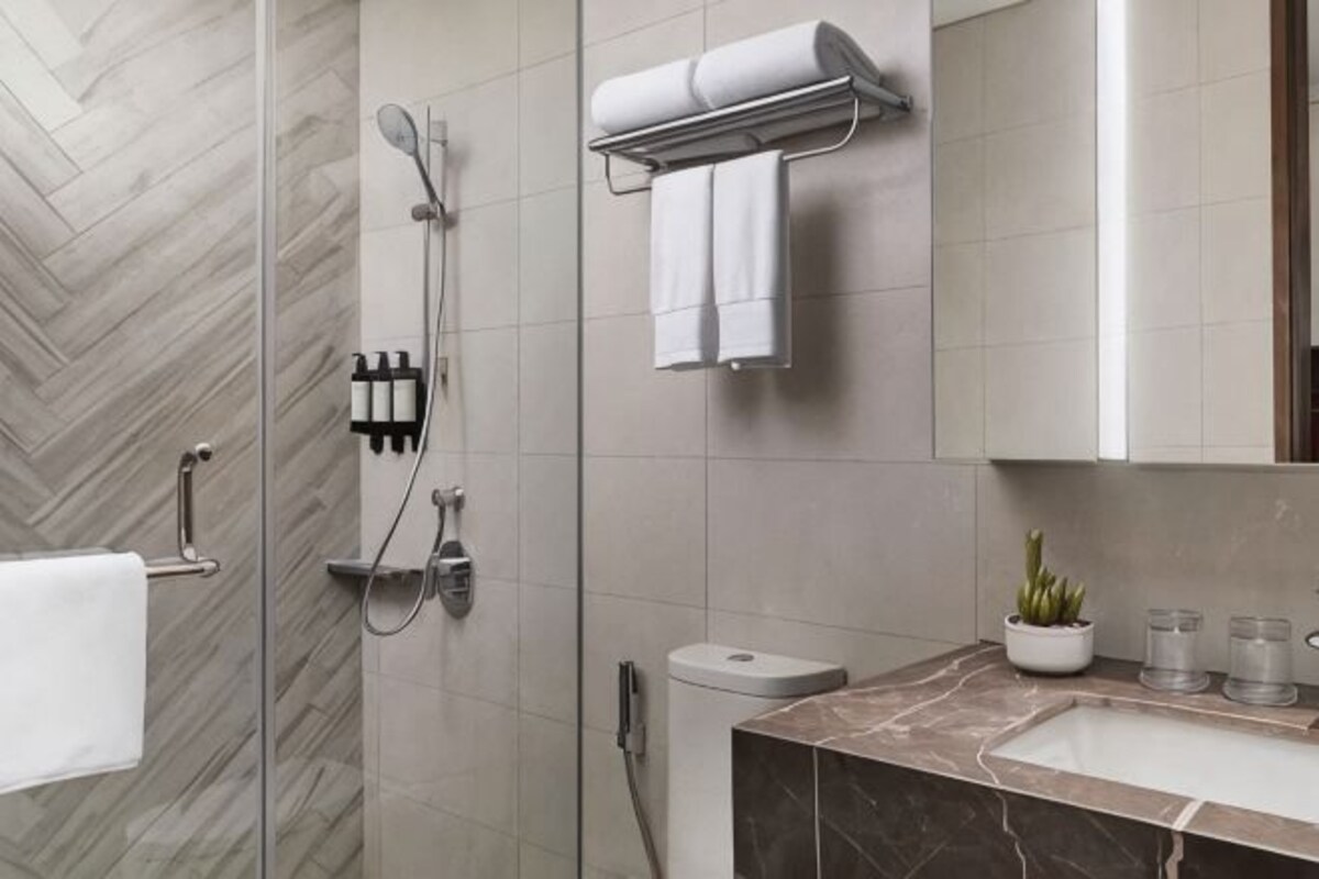 Een moderne badkamer met douche, toilet en wastafel.