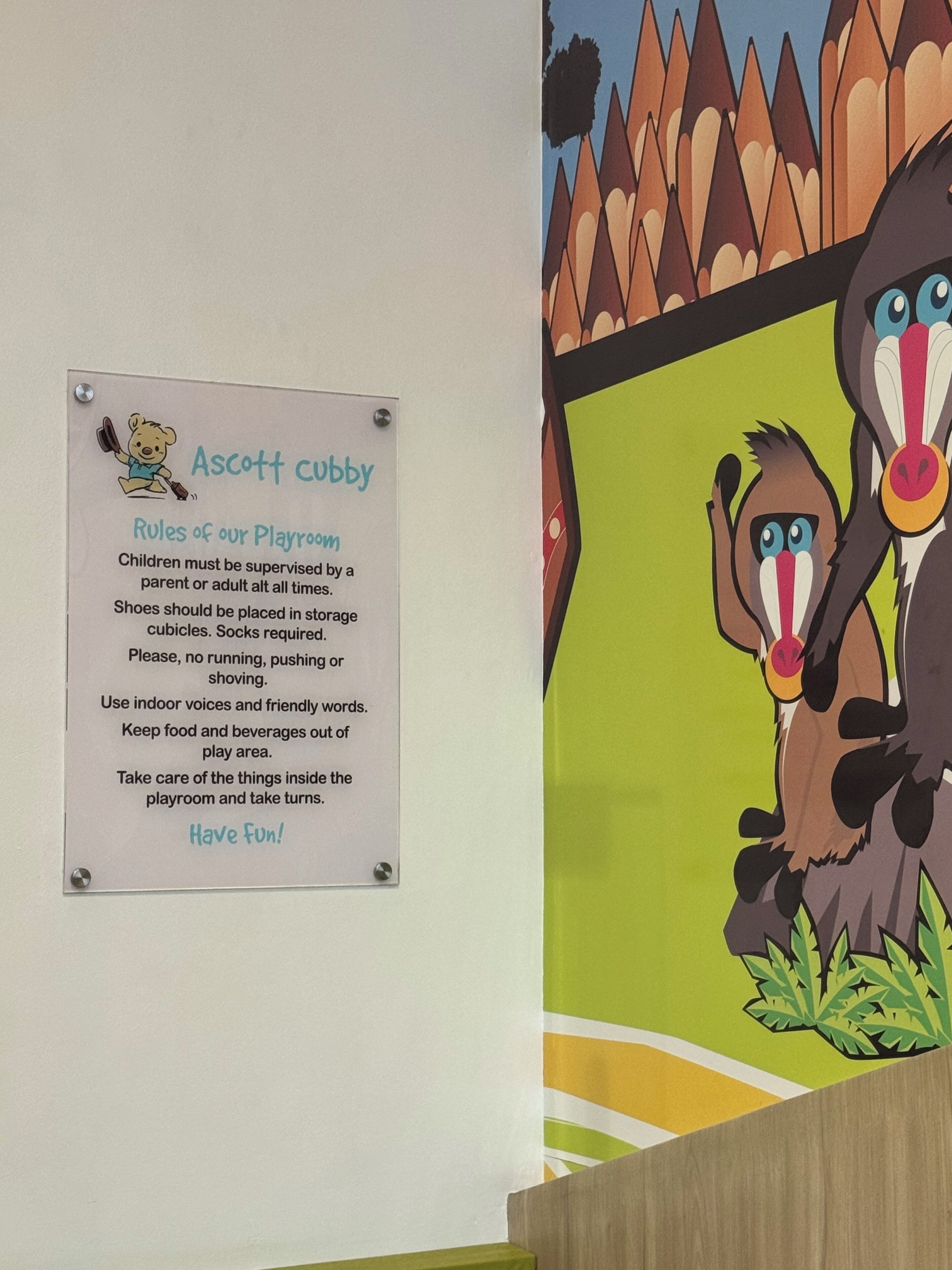 Un panneau indiquant les règles à respecter dans la salle de jeux, agrémenté d’une illustration colorée d’un ours.