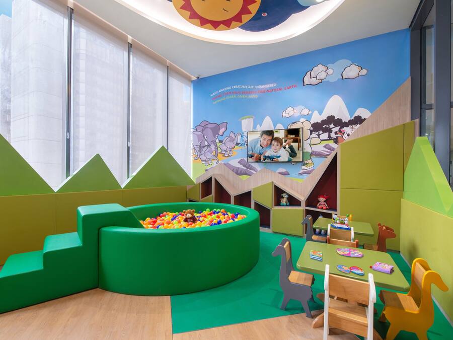 Ein Spielbereich für Kinder mit Bällebad, Sitzgelegenheiten und Wandgemälde.