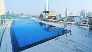 Una piscina infinita en la azotea con sillones de descanso y barandilla de cristal.