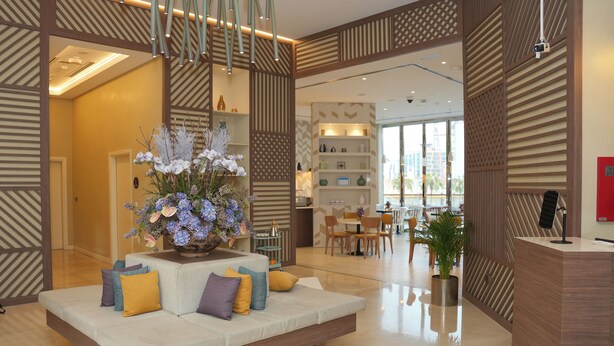 Un hall moderno con sofá, plantas decorativas y mostrador de recepción.