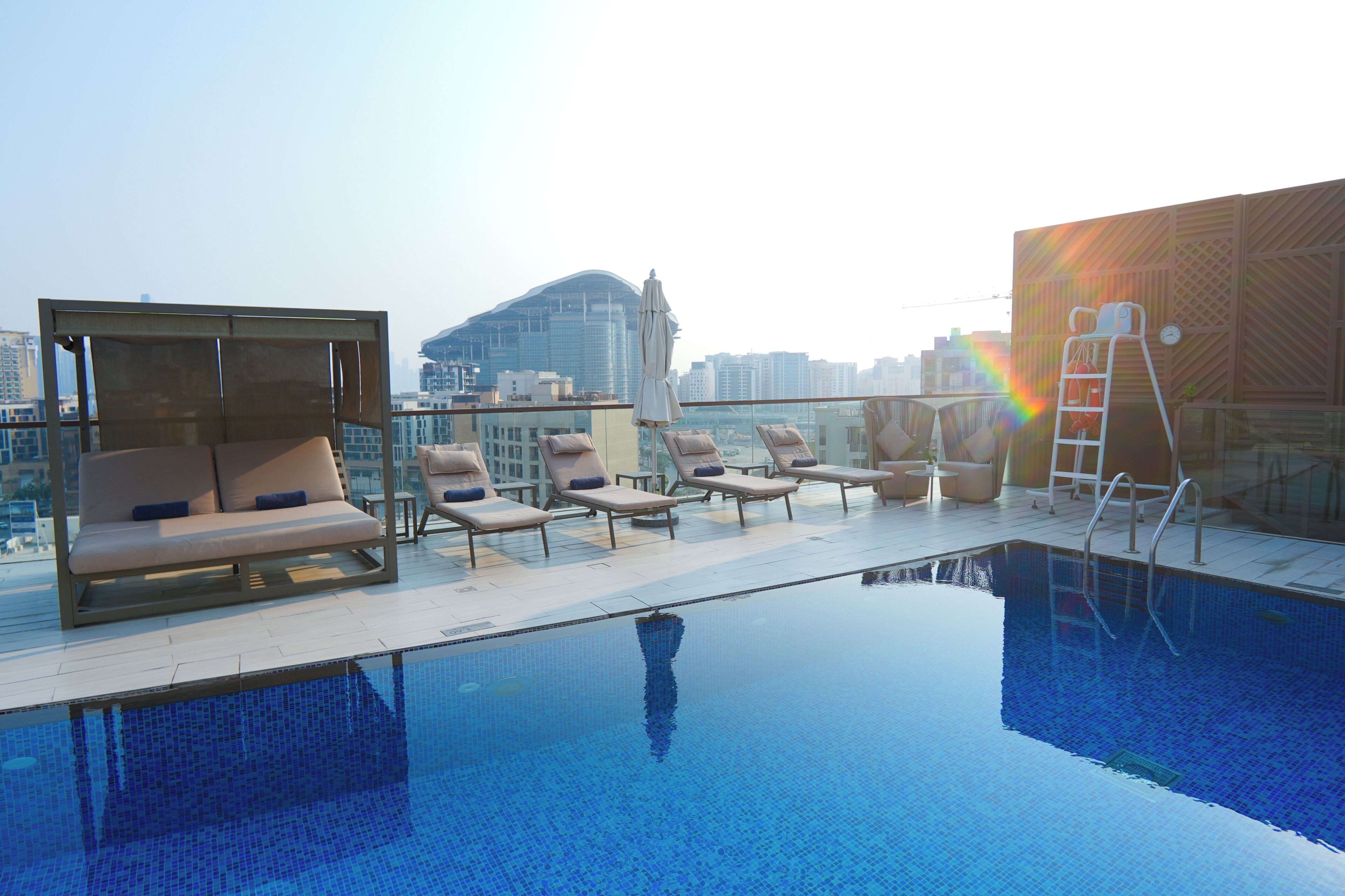 A rooftop pool area with lounge chairs and a view of a city skyline.