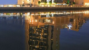 Un hotel moderno de gran altura con varias plantas, vistas al agua y su reflejo en el agua.