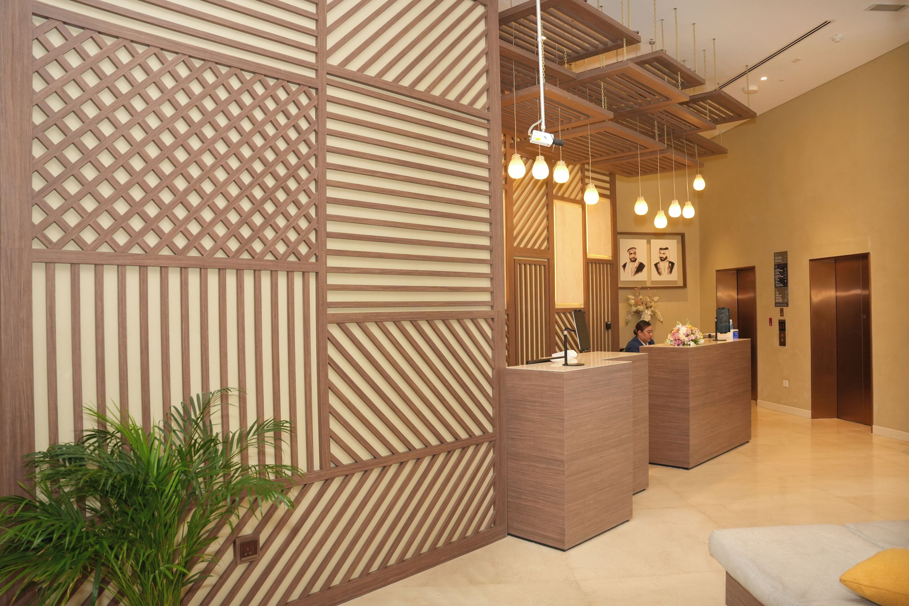 A reception area with a modern design, featuring a reception desk, a potted plant, and a seating area with a bench.