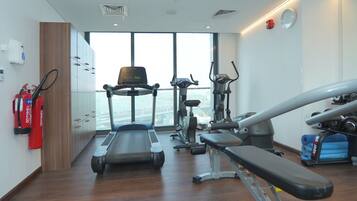 Une salle de sport équipée de machines de cardio, de bancs de musculation et d’une grande fenêtre donnant sur la ville.