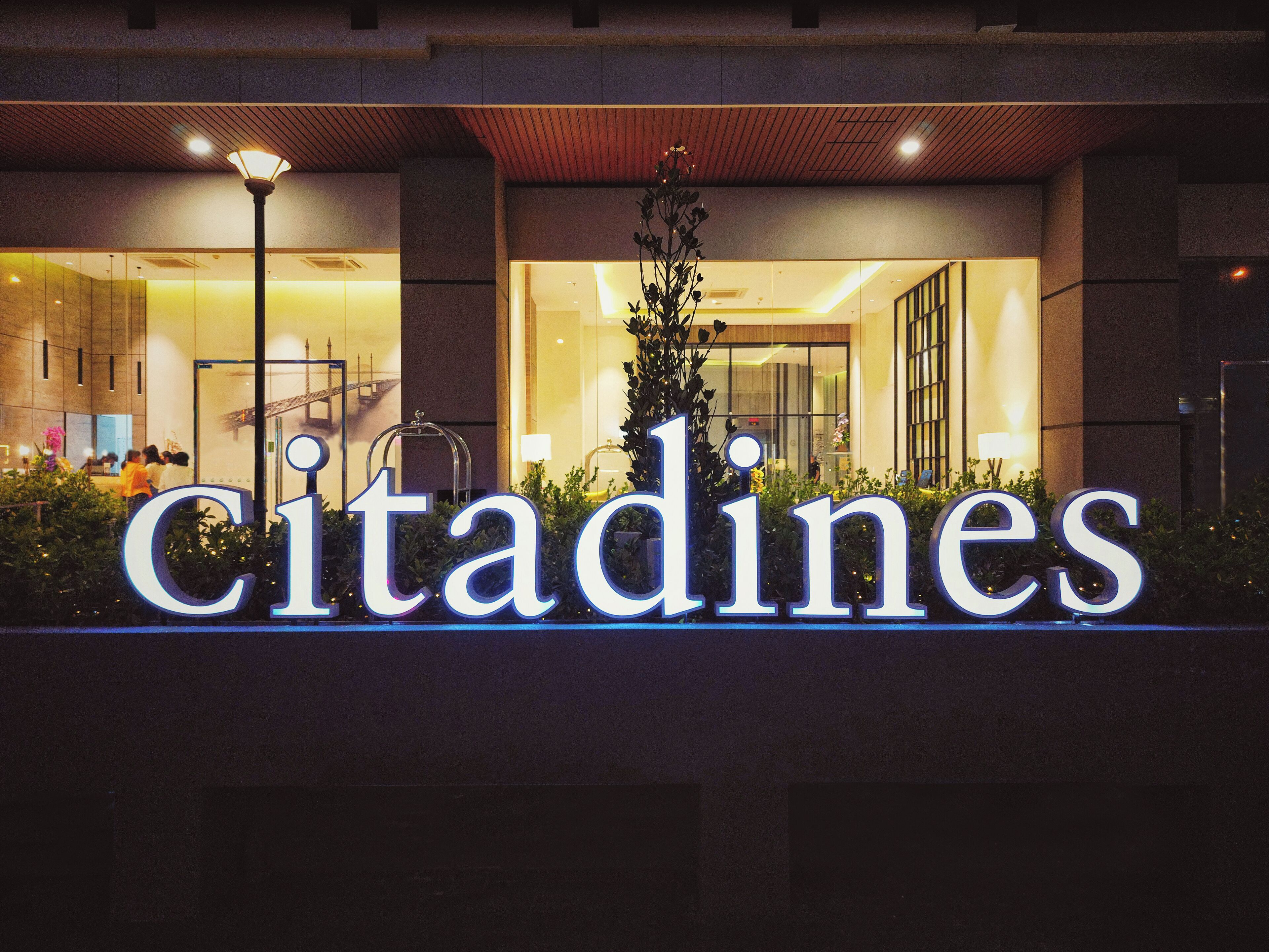 A hotel entrance with a large illuminated sign reading "Citadines".