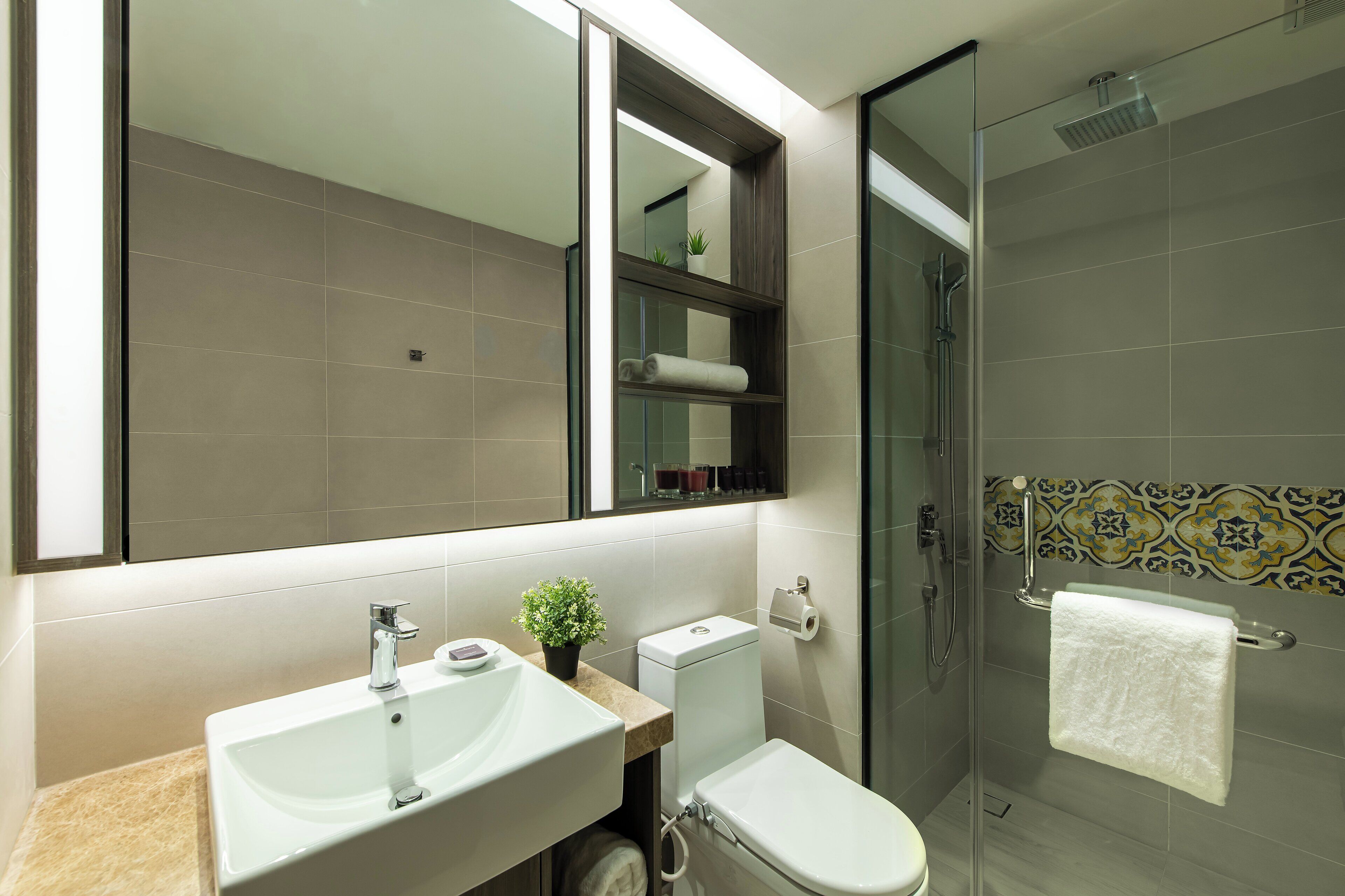 A modern bathroom with a glass shower enclosure, a large mirror, and a sink with a countertop.
