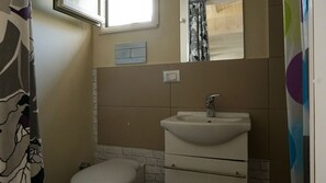 Ein kleines Badezimmer mit einem weißen Waschbecken, einer Toilette und einem Fenster über dem Waschbecken.
