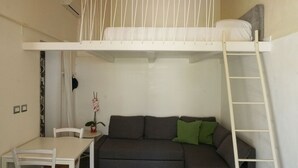 A compact room with a bunk bed, a sofa, a small table, and a chair. - Dependance in Villa con Piscina by Wonderful Italy (Siracusa)