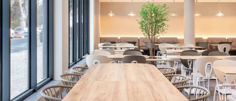 Un comedor moderno con una gran mesa de madera, varias sillas y lámparas colgantes.
