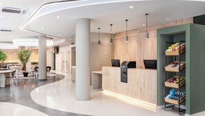 A modern reception area with a curved desk, seating, and a self-service kiosk. - B&b Hotel Lisboa Montijo (Montijo)