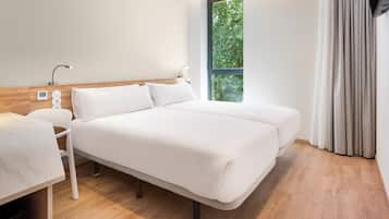 A modern hotel room with a large bed, bedside tables, a desk, and a window with curtains.