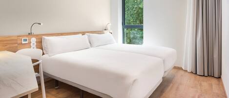 A modern hotel room with a large bed, bedside tables, a desk, and a window with curtains.