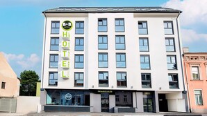Un moderno edificio de hotel con un llamativo letrero de B&B Hotels, numerosas ventanas y una zona de recepción.