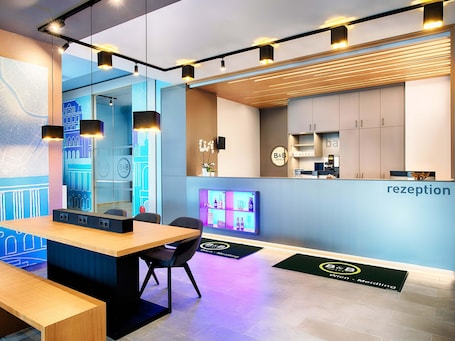 A modern hotel reception area with a reception desk, seating, and a wall-mounted map.
