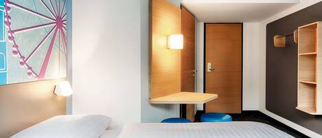 A modern hotel room with a bed, a small desk, a wall-mounted shelf, and a large wall art of a Ferris wheel.