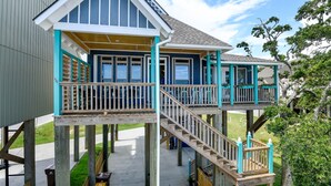 A two-story wooden deck with a staircase and railings, connected to a house with blue trim and white windows. - Luxury Beach Front Home!!! (Long Beach)