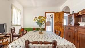 A dining area with a table set for four, a vase of flowers, and wooden furniture. - Spacious apartment just minutes from the beaches of the Maldives of Salento (Pescoluse)