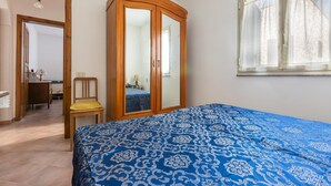A bedroom with a bed, a wooden wardrobe, a chair, a desk, and a window. - Spacious apartment just minutes from the beaches of the Maldives of Salento (Pescoluse)