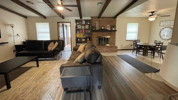 A spacious living room with a fireplace, a dining area, and a black leather couch.