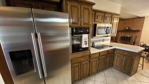 A kitchen with stainless steel appliances, wooden cabinets, and a tiled floor.