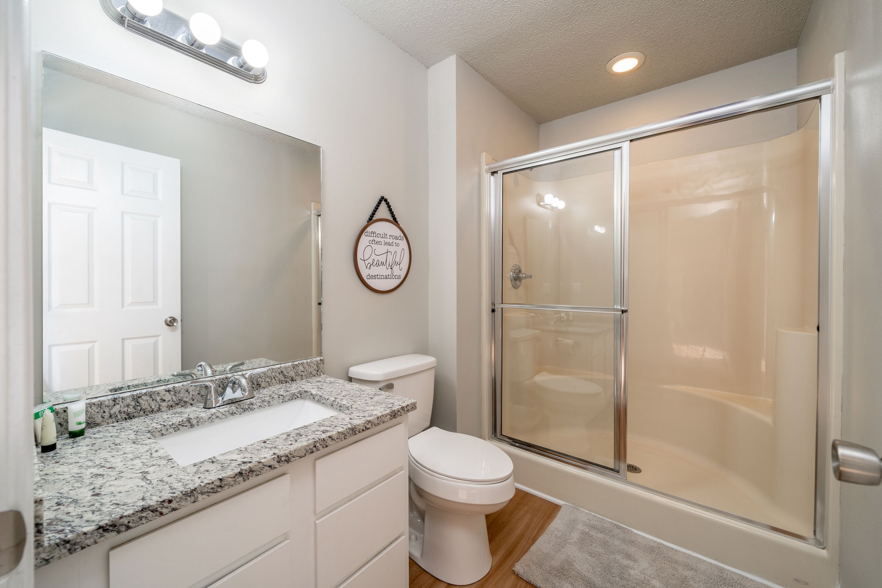 Une salle de bain avec un lavabo blanc, des toilettes et une douche à parois de verre.