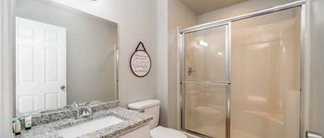 A bathroom with a white sink, a toilet, and a glass-enclosed shower.