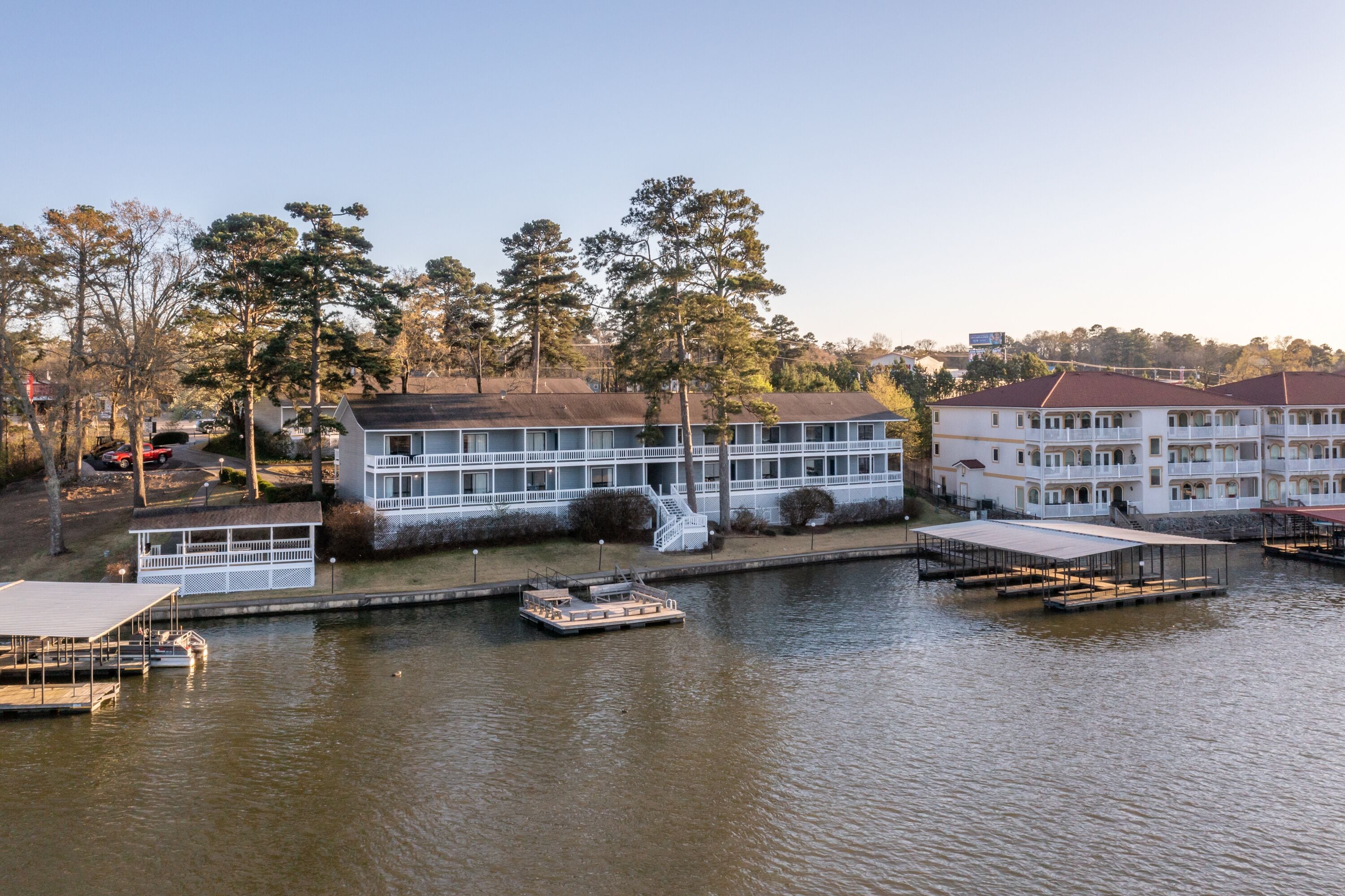 A waterfront hotel with a dock, a boat, and a large building with multiple balconies.