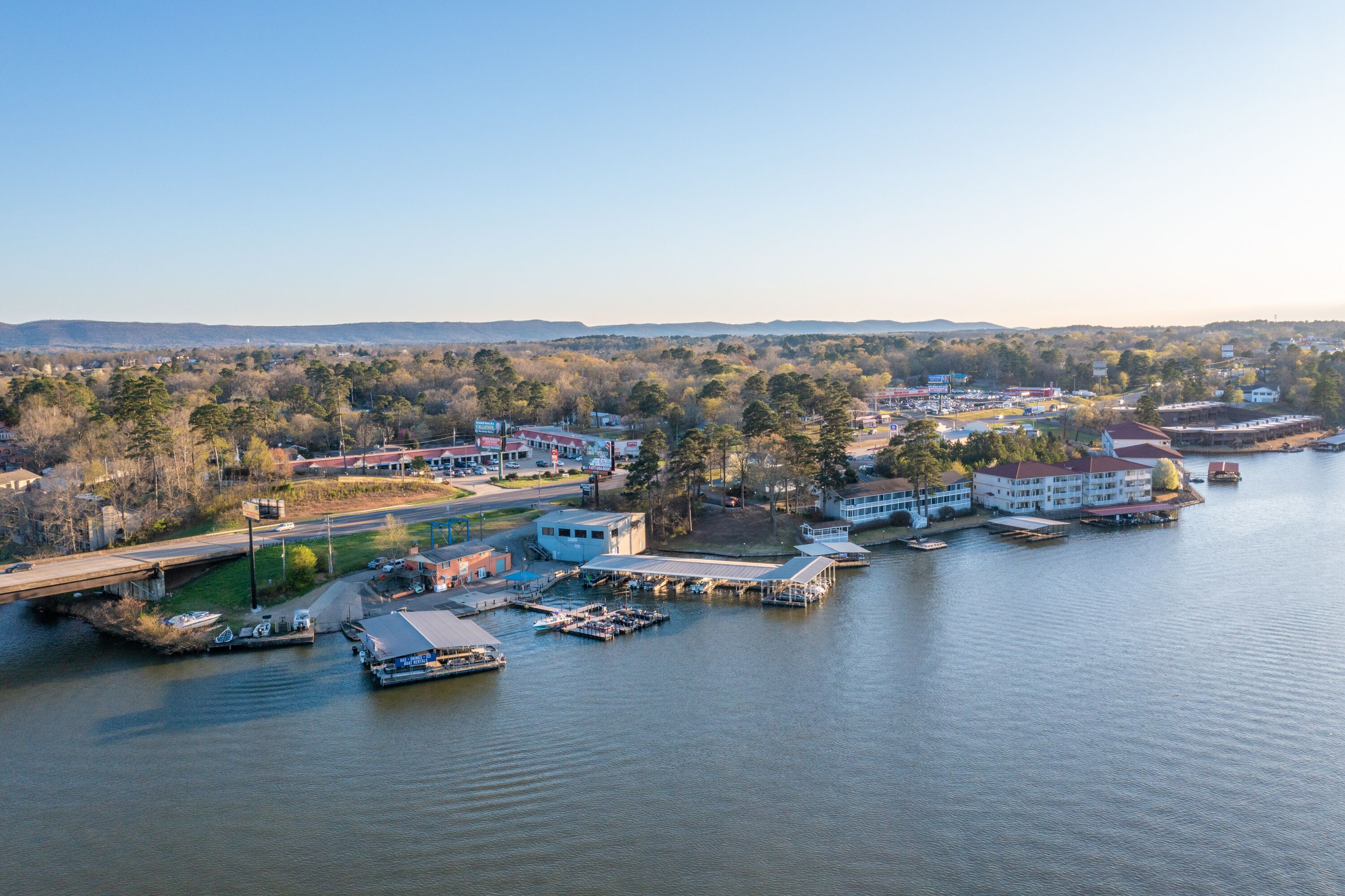 A waterfront property with a dock, boats, and a building with a red roof.