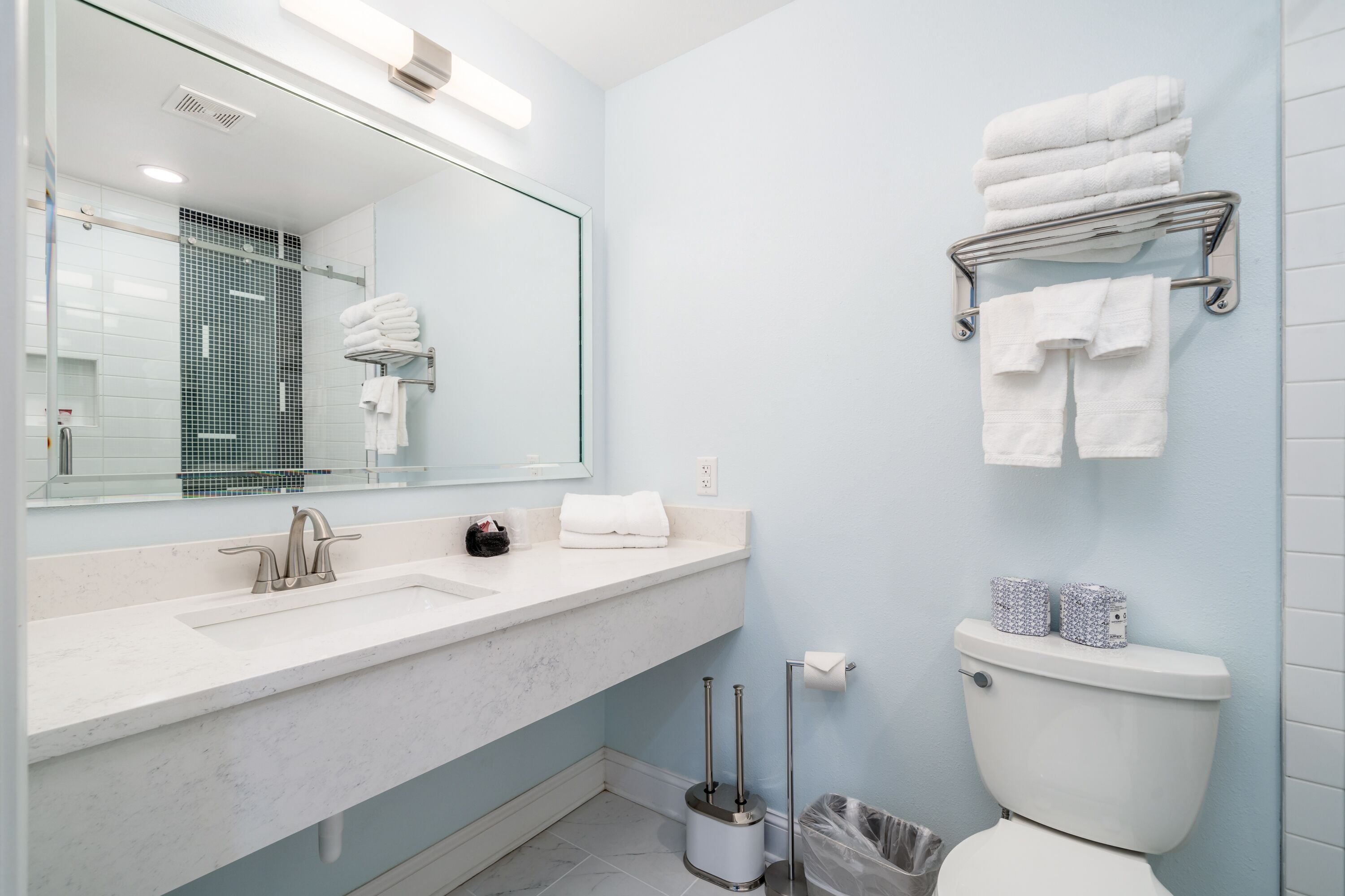 Une salle de bain moderne avec un grand miroir, un lavabo, des toilettes et un porte-serviettes.