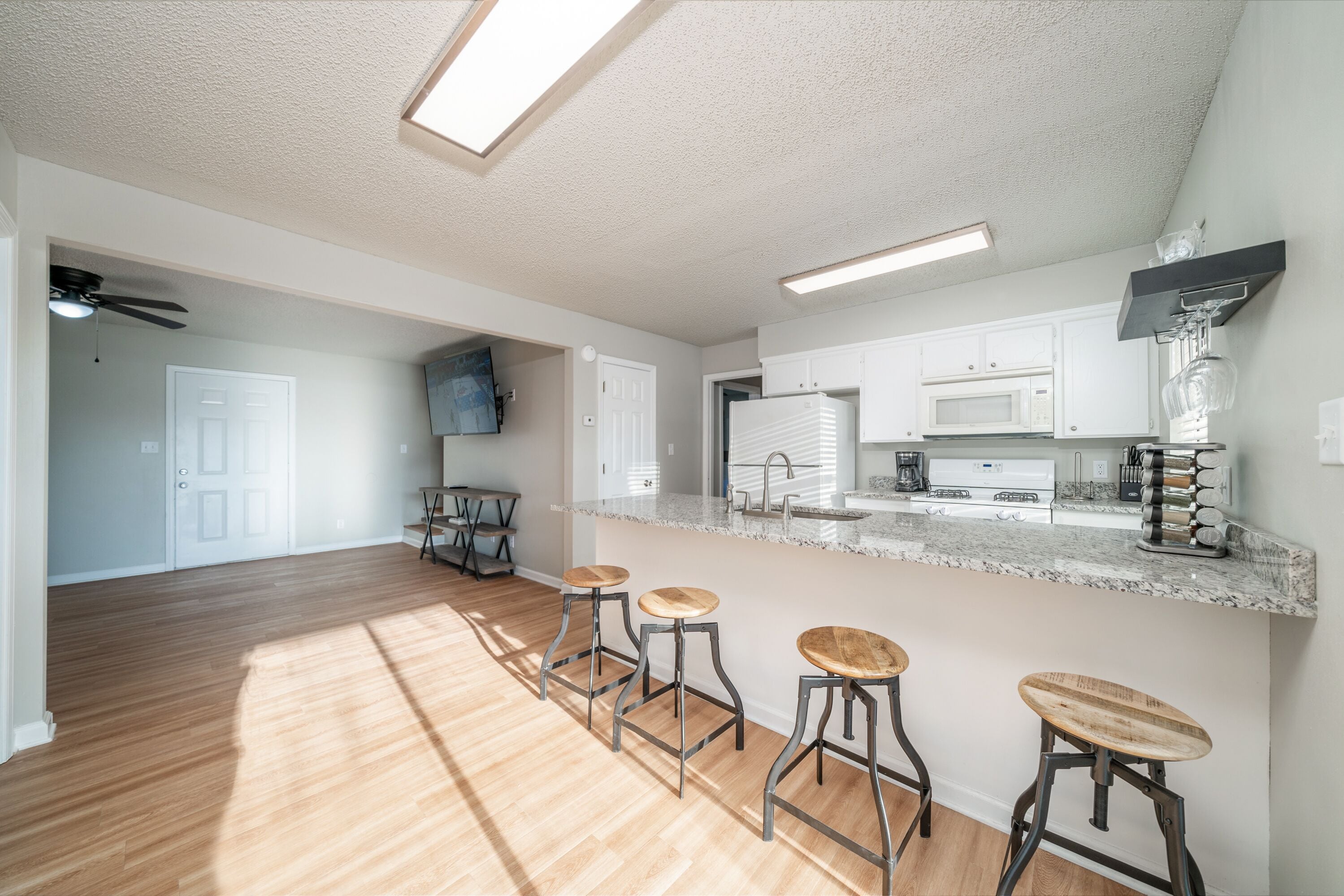 Una cocina moderna con barra, piso de madera y ventilador de techo.