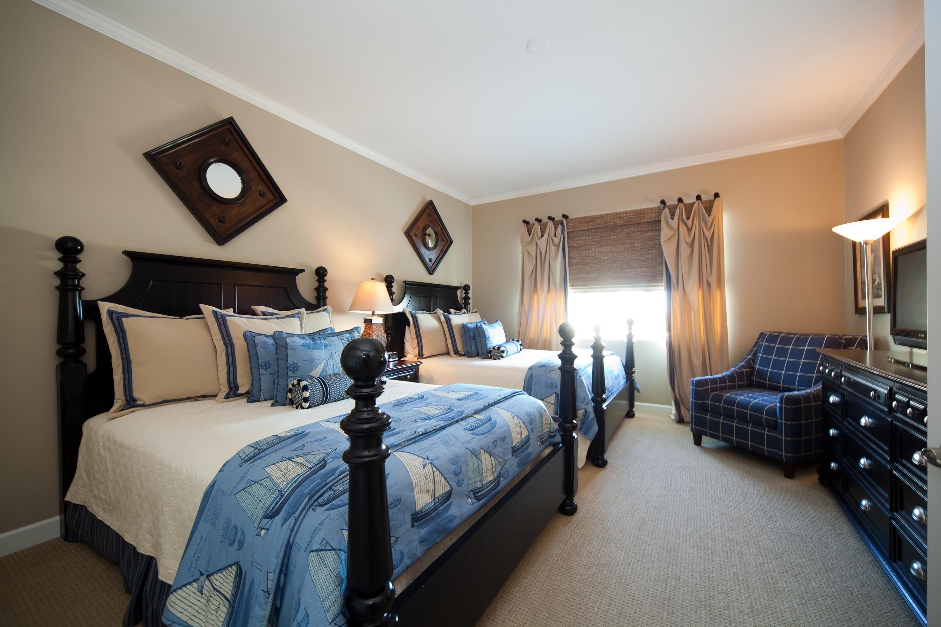 A hotel room with two beds, a dresser, a chair, and a television.