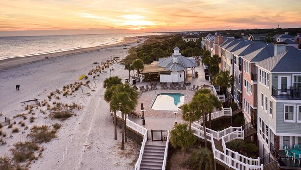 Ein Strandhotel mit Pool, Zugang zum Strand und Blick auf den Sonnenuntergang.