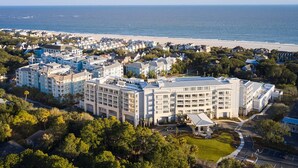 Ein Küstenhotel mit mehreren Gebäuden, einem Strand im Hintergrund und umliegender Bepflanzung.