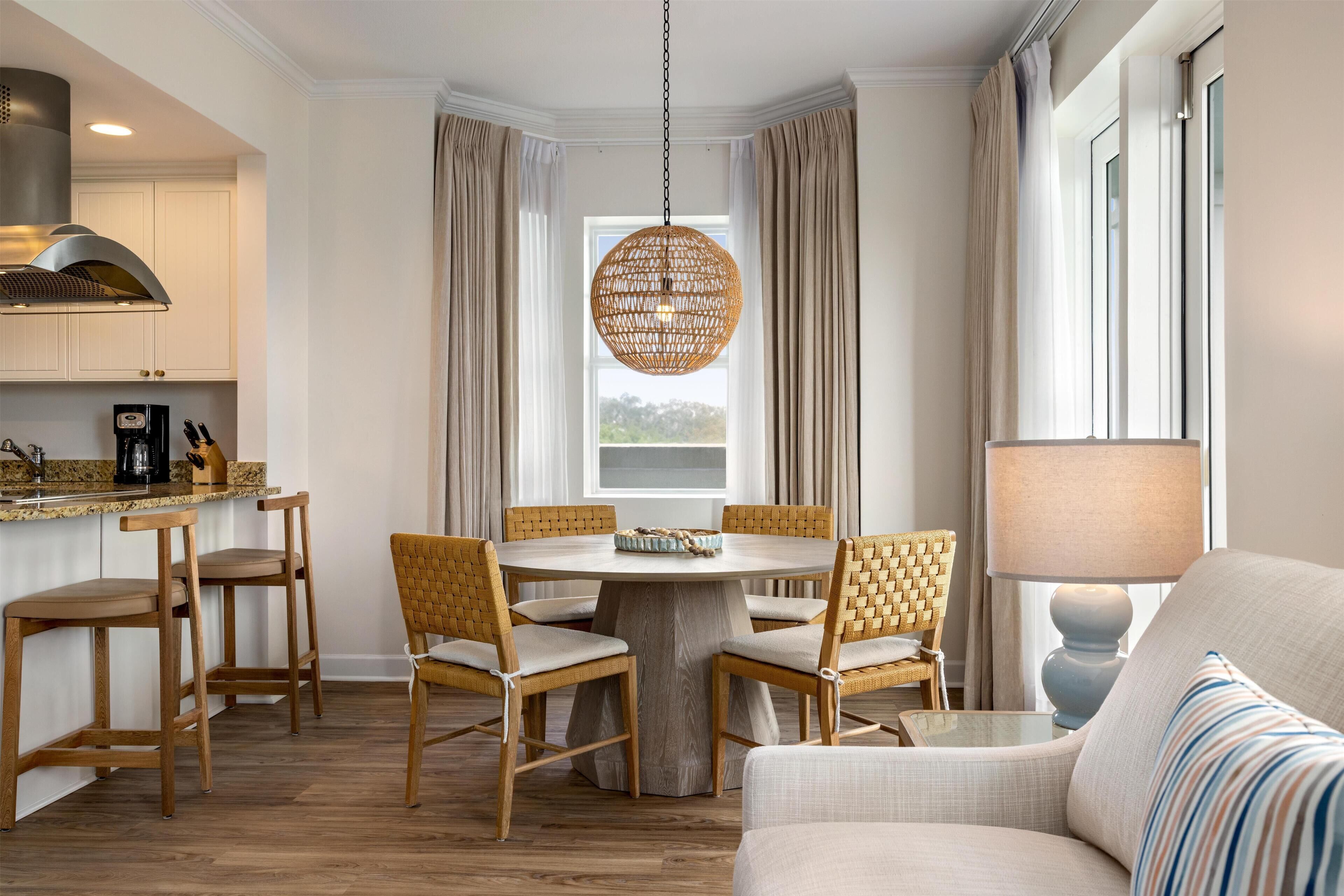 A modern dining area with a round table, wooden chairs, and a hanging light fixture.